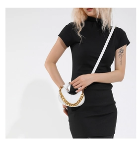 White crescent leather mini bag with decorative gold chain strap on female model