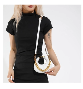 White crescent leather bag with gold chain strap shown on model with black dress