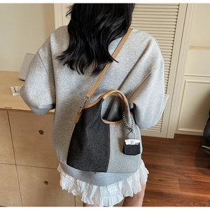 Detail of grey denim patchwork bucket bag with leather strap shown in home setting