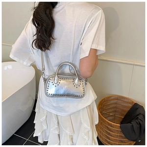 Detail of silver rivets and metallic texture on a stylish oval PU leather handbag