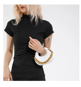 Detail of white crescent bag with lychee texture and bold gold chain strap