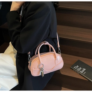 Pink retro bowling bag with silver lock charm shown on model against dark background