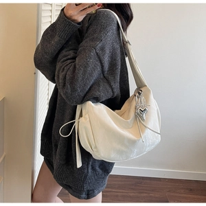 Detail of white crescent bag with soft texture, side drawstrings and silver heart charm