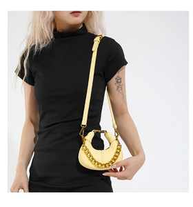 Détail d'un mini sac demi-lune jaune vif avec une grosse chaîne en métal doré chic