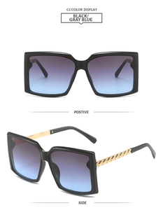 Détail de lunettes de soleil carrées noires avec verres dégradés et branches en chaîne
