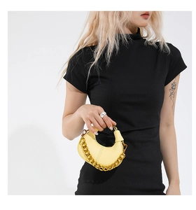 Close-up of yellow crescent bag with litchi texture and bold gold chain handle detail
