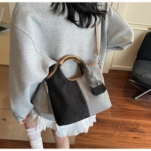 Two-tone denim bucket bag with brown leather handles and a mini charm pendant on model