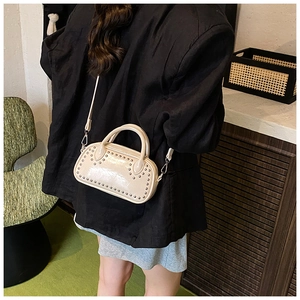 Detail of beige rivet studded crossbody bag styled with a professional black blazer look