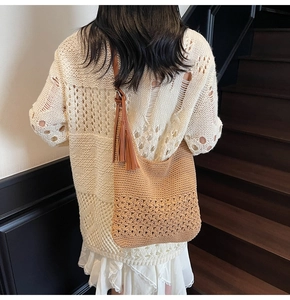 Close-up of hand-woven shoulder bag with intricate hollow patterns and long side tassels