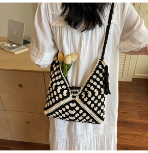 Detail of black and white crochet shoulder bag with stylish tassels and geometric pattern