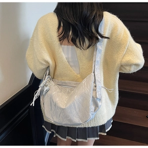 Silver pleated large capacity shoulder bag shown on model in a minimalist stair setting