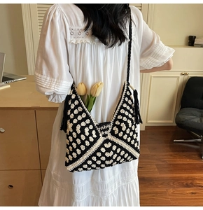 Detail of hand-woven crochet tote bag with black and white geometric patterns and tassels