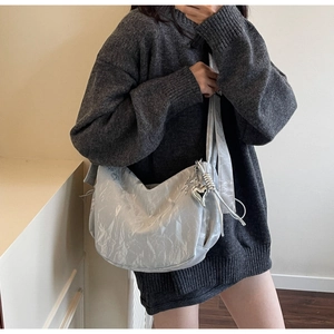 Close-up of silver hobo bag with pleated texture and metallic heart charm detail