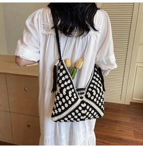Detail of hand-woven crochet tote bag with black and white geometric patterns and tassels
