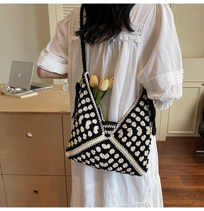 Detail of bohemian knit tote bag featuring black and white geometric patterns and side tassels