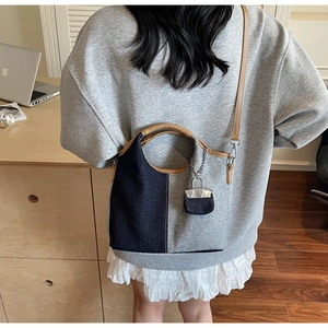 Blue canvas bucket bag with brown PU handle and adjustable strap worn by a model