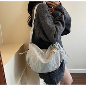 Detail of light grey hobo bag with silver heart pendant and glossy wrinkled texture