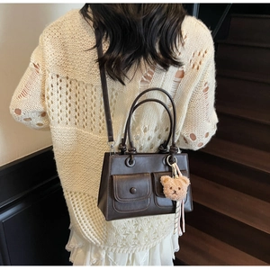 Brown vintage handbag with small front pockets and a cute plush bear charm detail