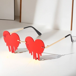 Gros plan de lunettes de soleil en forme de cœur rouge avec détails de gouttes dorées