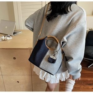 Detail of the high-quality canvas bucket bag with leather handles and mini lock charm