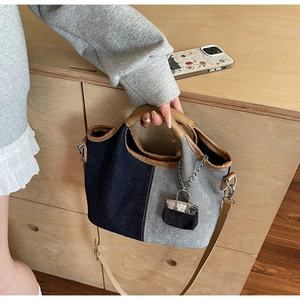 Detail of two-tone denim bucket bag with brown leather handles and matching mini purse