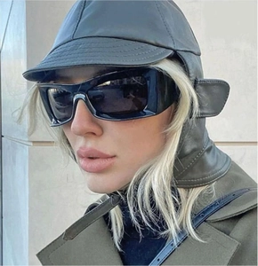 Close-up of stylish oversized square sunglasses paired with a leather trapper hat