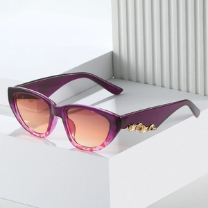 Detail of purple cat-eye sunglasses with gradient orange lenses and golden metal temples