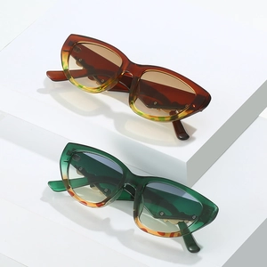 Detail of cat eye sunglasses in gradient amber and green on geometric display stands