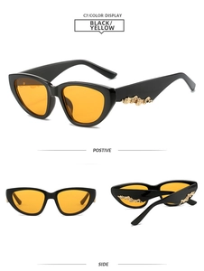 Detail view of black cat-eye sunglasses with yellow lenses and golden wave temple decor