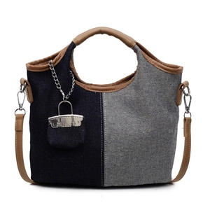 Minimalist patchwork denim bucket bag with brown leather handles and silver chain charm