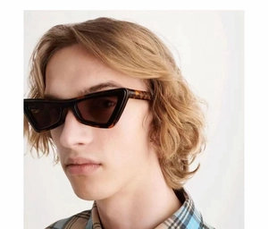 Detail of tortoiseshell geometric cat-eye sunglasses with thick acetate frame on a model
