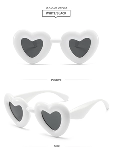 White heart-shaped Y2K sunglasses with thick frames and dark lenses seen from side and front