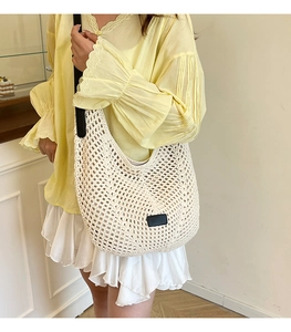 Detail of white crochet hobo tote bag with black leather patch and shoulder strap