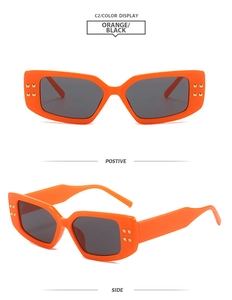 Detail of stylish orange square sunglasses with gold stud rivets and dark lenses