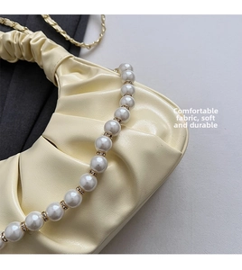 Detail view of beige pleated cloud bag with pearl chain strap and soft leather texture