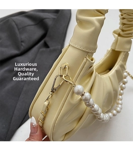 Detail of light yellow cloud bag featuring gold hardware and elegant pearl chain handle
