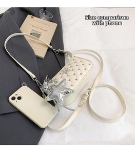 Size comparison of beige quilted crossbody bag with a smartphone and silver star charm