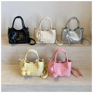 Détail de sacs seaux tressés en cinq couleurs avec breloques et bandoulières fines