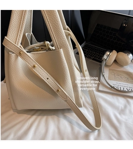 Detail of white lychee leather bucket bag with gold hardware and adjustable strap