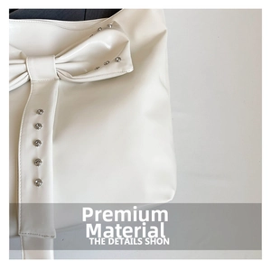 Detail of studded leather bow and silver rivets on a cream white designer tote bag