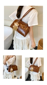 Détail du sac Boston vintage en cuir marron avec breloque ours et logo de la marque