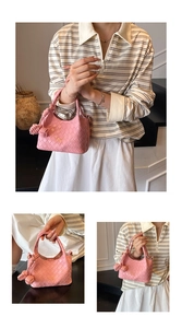 Détail du sac seau rose tressé avec poignée à nœud et lettrage doré élégant