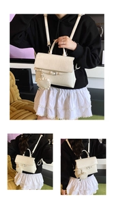 Detail of cream faux leather backpack with litchi texture and decorative heart charm