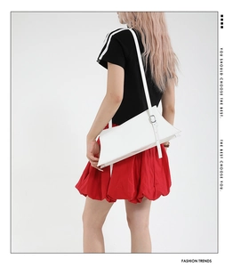Détail d'un sac à épaule blanc en cuir avec boucle argentée et design incurvé élégant