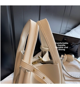 Detail of reinforced leather handle with metallic rivets on off-white bucket bag
