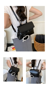 Detail of black patent leather backpack with top handle and white lace heart charm