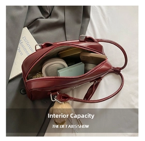 Intérieur spacieux d'un sac Boston en cuir verni bordeaux avec charm ours en peluche