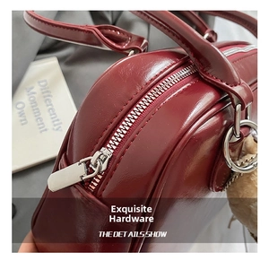 Détail d'un sac à bandoulière rouge foncé fini brillant avec boucles en métal argenté