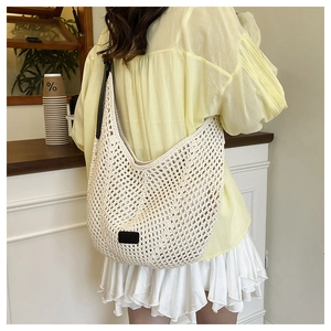 Detail of beige crochet hobo bag with black leather strap and square patch on a model