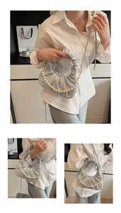 Detail of light blue pleated cloud bag with pearl handle and golden chain strap
